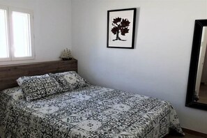 Ein Schlafzimmer mit einem Bett, einem gerahmten Bild an der Wand und einem Fenster.