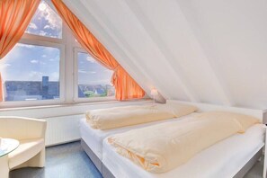 Un dormitorio con dos camas, una ventana con cortinas, un escritorio y una silla.