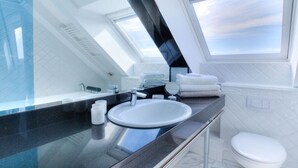 Casa de banho moderna com clarabóia, lavatório branco e sanita.