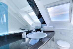 Un baño moderno con tragaluz, un lavamanos blanco y un inodoro.
