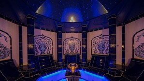 Quarto luxuoso com piscina central, designs ornamentais nas paredes e teto estrelado.