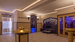 Um saguão com balcão de recepção, parede decorativa com padrão floral e área de estar com iluminação azulada.