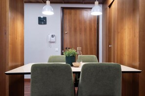 Sala de conferência com porta de madeira, telefone, planta e mesa com cadeiras.