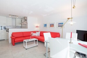Ein modernes Wohnzimmer mit einem roten Sofa, einem weißen Couchtisch und einem Glastisch.