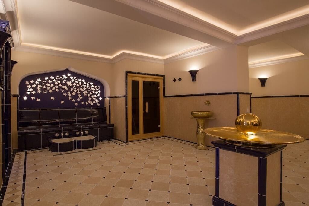 Un hall d’hôtel comprenant un comptoir d’enregistrement, un bureau de réception et un mur décoratif orné d’un motif de feuilles.