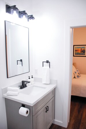 A modern bathroom with a white sink, two mirrors, and a toilet paper holder. - NEW Charming Cottage in Rockport, Sunset Views, Dog-friendly - Sleeps 6 (Rockport)