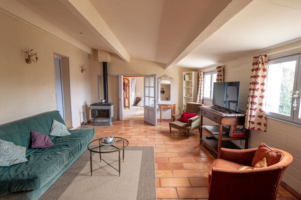 A cozy living room with a sofa, armchair, and a television.