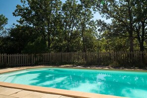 Ein von Bäumen und einem Holzzaun umgebener Pool.