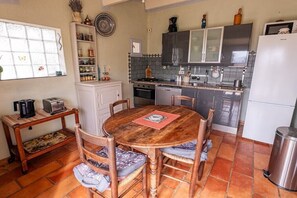 Eine kleine Küche mit Esstisch, Stühlen und Kühlschrank.