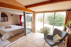 Ein Schlafzimmer mit Bett, Sessel, Fenster und Blick ins Freie.