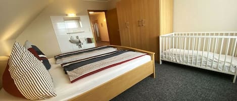 Een slaapkamer met een bed, een ledikant, een kledingkast, een spiegel en een wastafel.
