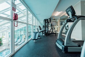 Une salle de sport équipée de matériel d’exercice, d’un tapis de course et d’un téléphone rouge pour les urgences.