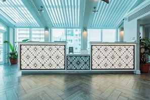 A reception area with a modern design, featuring a herringbone wood floor, a geometric patterned partition, and a view of the cityscape through large windows. - North Myrtle Beach | Marsh Escape | Pool & Beach Access | 2BR Villa (North Myrtle Beach)
