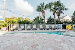 A swimming pool with lounge chairs, palm trees, and a fenced area. - North Myrtle Beach | Marsh Escape | Pool & Beach Access | 2BR Villa (North Myrtle Beach)