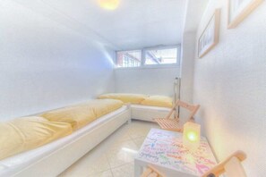 A small, bright room with a bed, a table with a light, and a window. - Holiday apartment in Sylt with 1 bedroom (Wenningstedt)