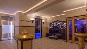 Un hall d’entrée spacieux au design moderne, comprenant un espace salon central, un mur décoratif orné d’un motif étoilé et une grande fontaine dorée.