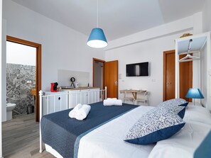 Une chambre d’hôtel moderne équipée d’un lit, d’un bureau, d’une télévision et d’une salle de bain.