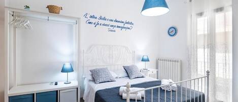 Un dormitorio con cama, mesitas de noche, armario, lámpara colgante y un reloj de pared.