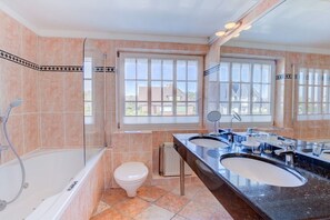 Ein Badezimmer mit einer Badewanne, zwei Waschbecken, einer Toilette und einem Fenster.
