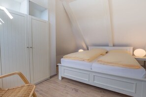 A bedroom with a bed, bedside table, and a wardrobe. - Holiday apartment in Sylt with 1 bedroom (Wenningstedt)
