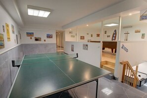 A room with a ping pong table, a staircase, and various wall decorations. - Holiday apartment in Sylt with 1 bedroom (Wenningstedt)