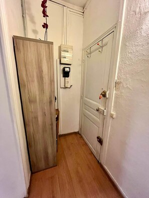 Ein schmaler Flur mit einem Holzschrank, einer weißen Tür mit Griff und einem an der Wand montierten Stromverteiler.