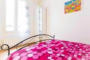 Ein Zimmer mit einem Bett, einem Fenster und einem Bild an der Wand.