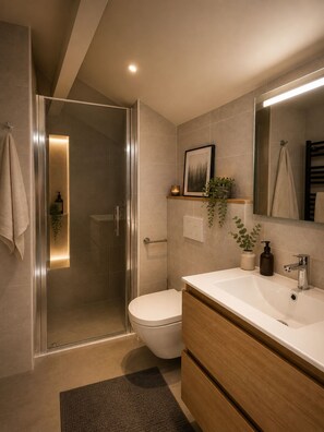 Un baño moderno con cabina de ducha de vidrio, inodoro, lavabo con espejo y tocador de madera.