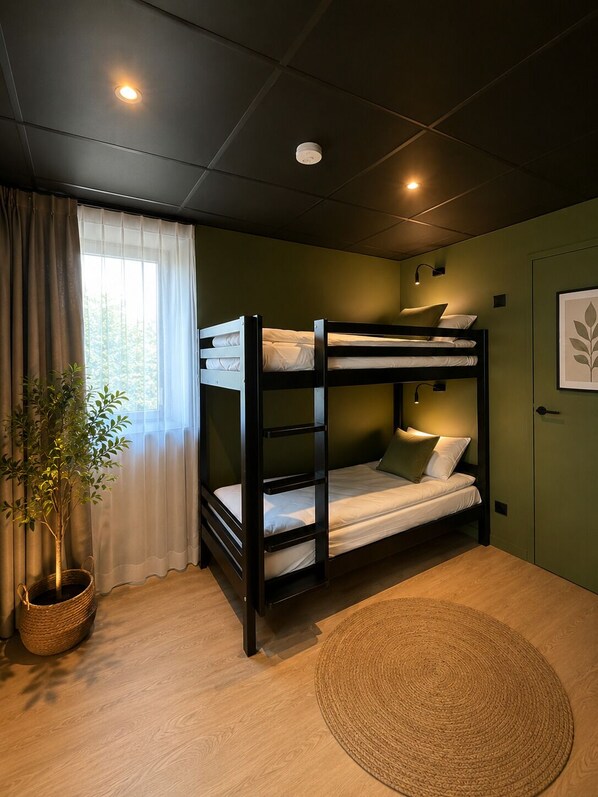 A bunk bed room with a window, curtains, a potted plant, and a round woven rug.