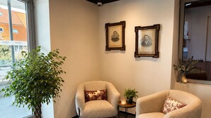 A modern interior with two armchairs, a potted plant, and framed pictures on the wall. - Résidence le 1900 (VULBENS)