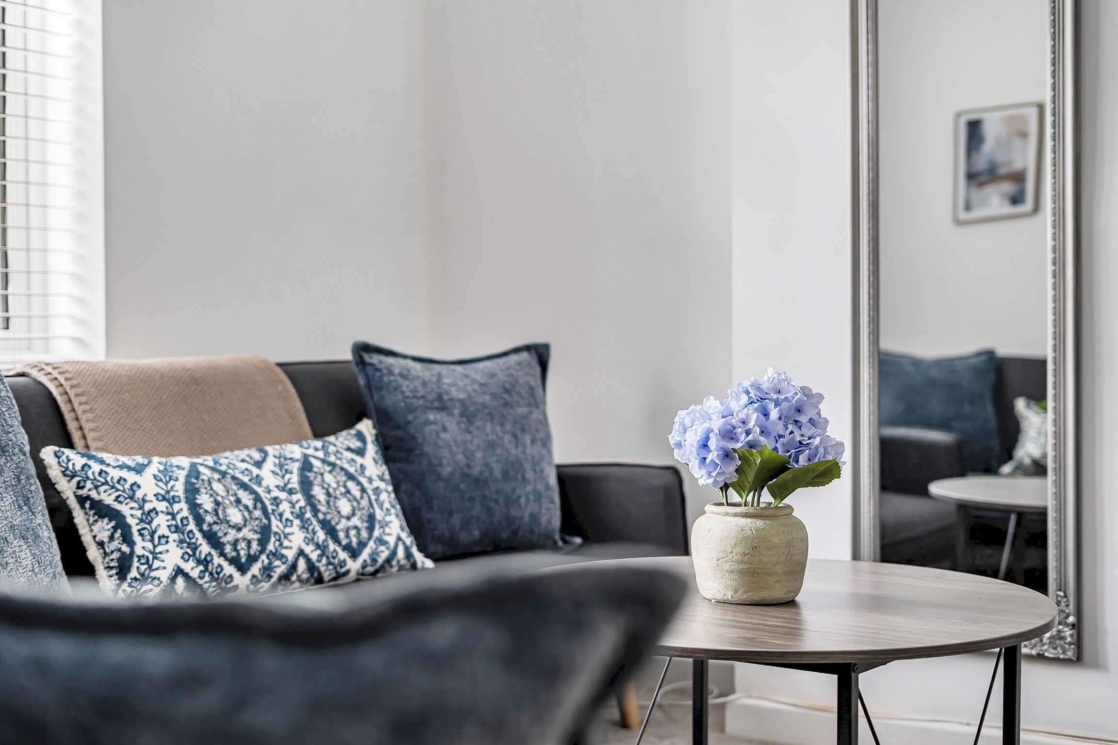 A modern living room with a sofa, a coffee table, and a vase with flowers.