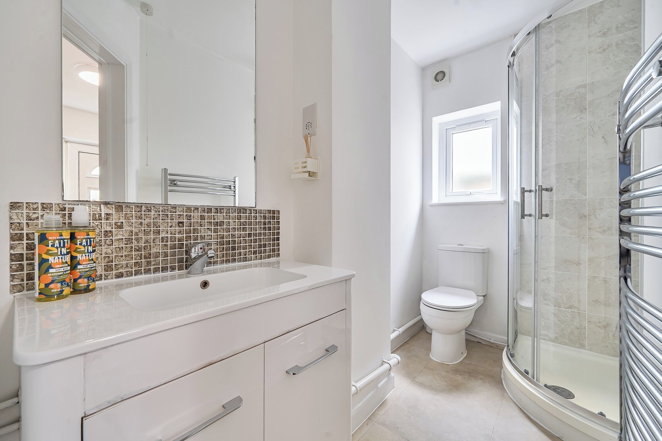 Ein Badezimmer mit einem weißen Waschbecken, einem Spiegel, einer Dusche mit Glastür und einer Toilette.