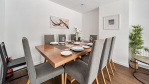 Et spiseområde med et træbord dækket til fire personer, omgivet af polstrede stole.