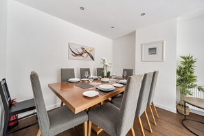 A dining area with a wooden table set for four, surrounded by upholstered chairs. - Surrey 5-Bed Home for Groups & Business Stays - Pass the Keys (Addlestone)