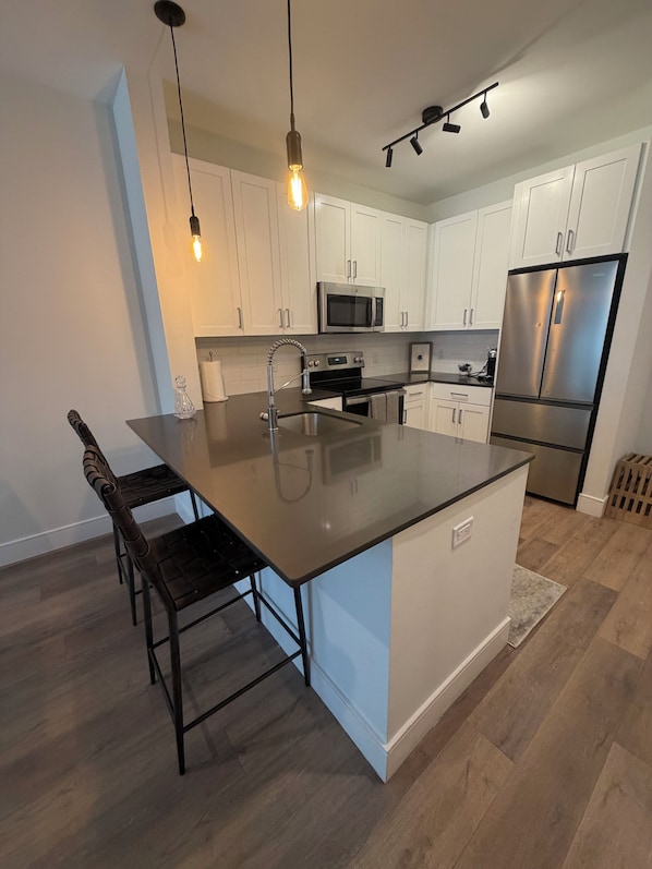 A modern kitchen with a central island, stainless steel appliances, and pendant lighting.