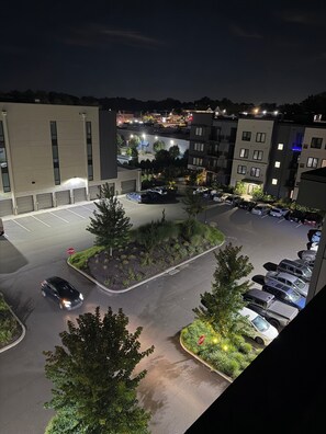 A parking lot with multiple cars, a stop sign, and a building with multiple floors.