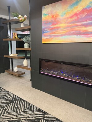 A modern interior with a fireplace, a bookshelf, and a colorful painting.