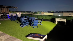 Een buitenzitplaats met stoelen en een tafelvoetbal tafel, omgeven door een verzorgd gazon.