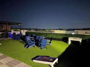 Un espacio al aire libre con sillas y una mesa de futbolín, rodeado por un césped bien cuidado.