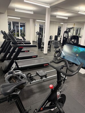Un gimnasio con cintas de correr, bicicletas estáticas y máquinas de pesas.