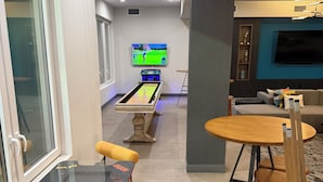 Een moderne woonkamer met een biljarttafel, een televisie en een zithoek.