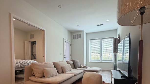 Een moderne woonkamer met een bank, een televisie en een groot raam.
