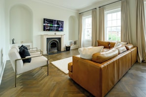 A living room with a fireplace, a sofa, a chair, and a television mounted on the wall. - Elegant Georgian townhouse to sleep 8, town centre - Pass the Keys (Shrewsbury)