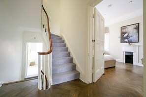 A staircase with a herringbone carpet pattern leading to a room with a fireplace and a painting on the wall. - Elegant Georgian townhouse to sleep 8, town centre - Pass the Keys (Shrewsbury)