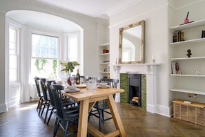 A dining room with a wooden table set for six, surrounded by black chairs, a fireplace, and a bookshelf with books and decorative items. - Elegant Georgian townhouse to sleep 8, town centre - Pass the Keys (Shrewsbury)