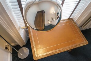 Un espejo circular que refleja una habitación con un armario de madera y una alfombra estampada.