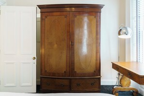 A wooden armoire with two doors and a drawer, positioned next to a desk and a lamp. - Charlie Chaplin House - A Historic Memorable Stay - Pass the Keys (Belfast)