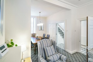 Quarto com mesa de jantar, cadeiras, sofá listrado, luminária e piso estampado.
