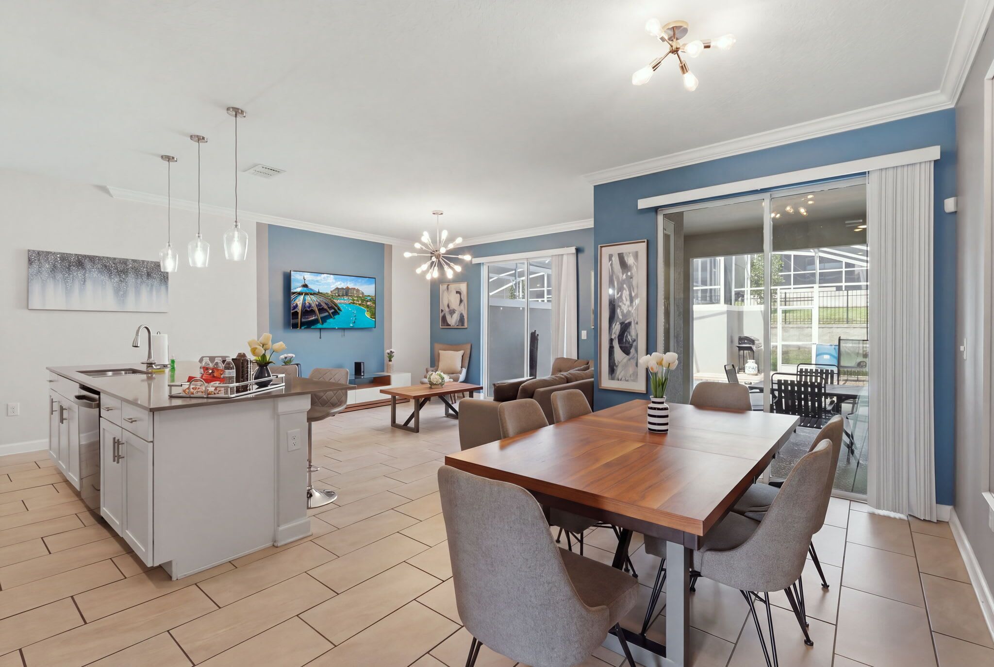 Een moderne keuken met een centraal eiland, een eethoek met een houten tafel en stoelen, en een groot raam met uitzicht op de omgeving.