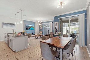 Een moderne keuken met een centraal eiland, een eethoek met een houten tafel en stoelen, en een groot raam met uitzicht op de omgeving.